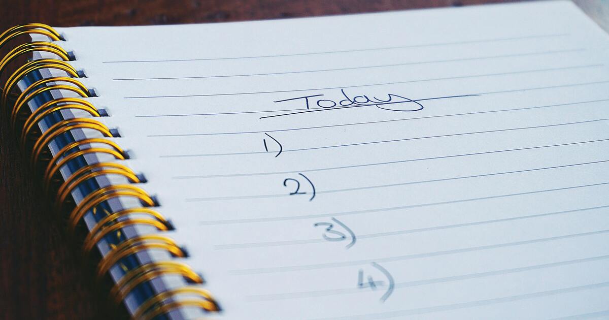 A person planning their day in a notebook, representing building a healthy daily routine